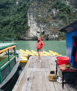 Woman standing on house over river against rock formations