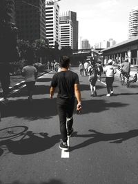 Rear view of man skateboarding on city street