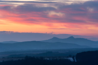 Scenic view of silhouette mountains against romantic sky at sunset