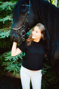 Young woman smiling while standing with horse