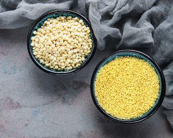 Raw couscous in a bowls on the grey concrete background