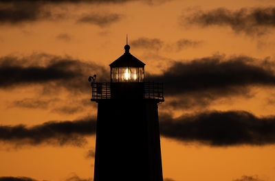 Lighthouse shines bright under a vibrant sunset on the bay