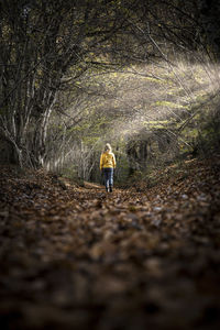 Rear view of woman walking on dirt road