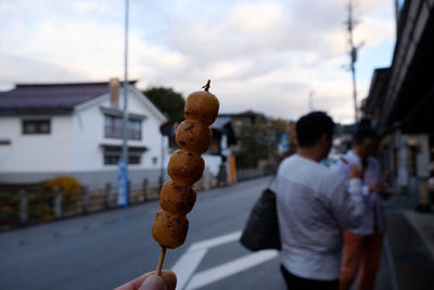 Man holding ice cream on street against buildings in city