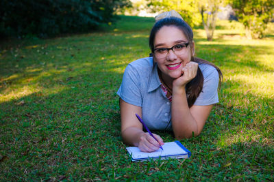 Portrait of young woman studying at park