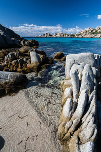 Rocks on beach against blue sky