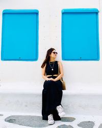 Full length of woman standing against blue wall