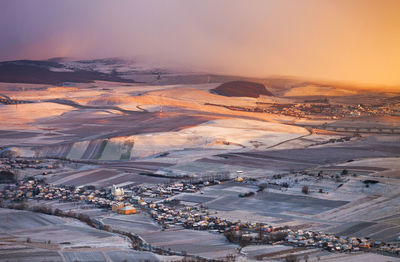 High angle view of snow covered landscape against sky during sunset