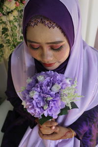 High angle view of bride wearing wedding dress while holding bouquet