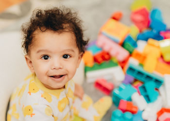 Portrait of cute boy sitting with toy at home