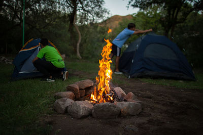 People adjusting tents at campsite during sunset