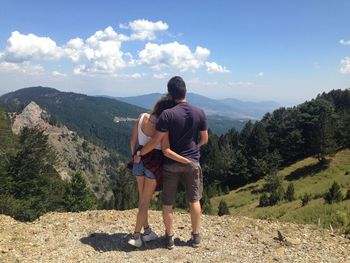 Rear view of man looking at mountains against sky