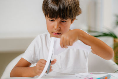 Child cutting cards with shapes in a preschool assessment test.