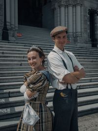 Portrait of smiling young couple wearing costumes standing against building