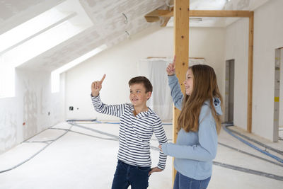 Sibling raising hand while standing at loft apartment