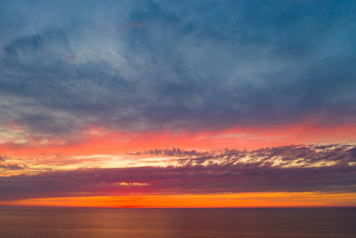 Scenic view of sea against dramatic sky during sunset