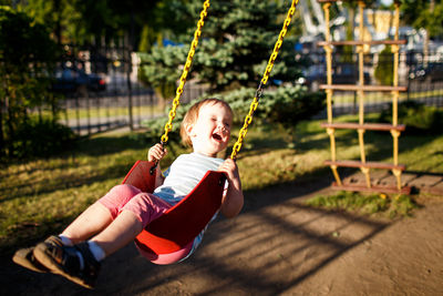 Cute girl swinging in park during sunny day