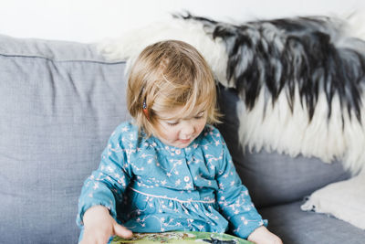 Cute girl sitting on sofa at home