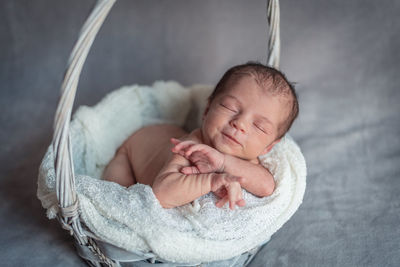 A newborn baby girl smiling in a basket while sleeping peacefully. newborn session concept
