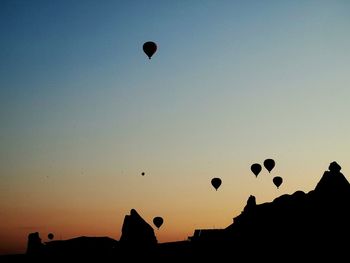 Silhouette hot air balloons against sky during sunset