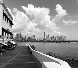 View of buildings by river against cloudy sky