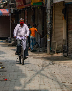 Man riding bicycle on street against buildings