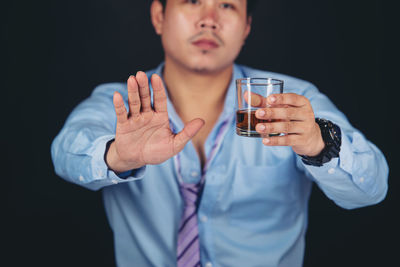 Midsection of man holding ice cream against black background