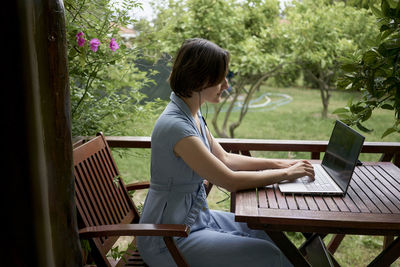 Freelancer working on laptop sitting on balcony