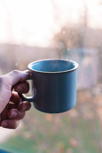 Close-up of hand holding coffee cup