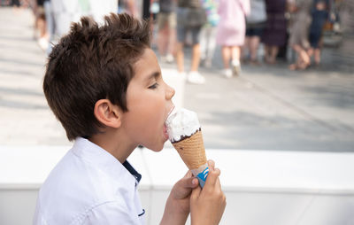 Cute child boy with a dirty face eats ice cream, the child enjoys dessert