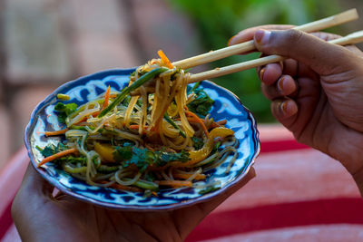 Midsection of person holding asian noodle salad