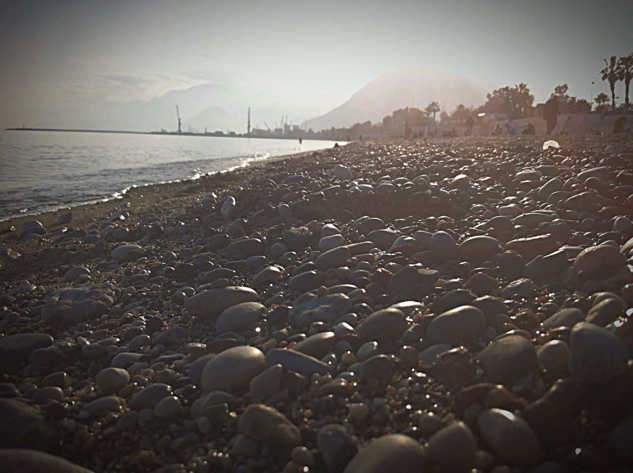 beach, sand, shore, water, sea, stone - object, sky, tranquil scene, pebble, tranquility, surface level, nature, scenics, beauty in nature, sunlight, rock - object, clear sky, outdoors, landscape, stone