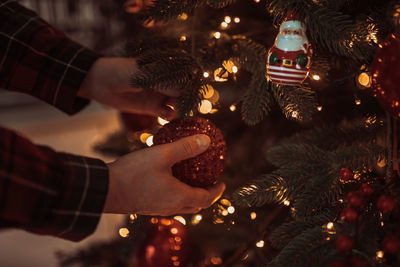 Cropped hand of man touching ornaments on christmas tree