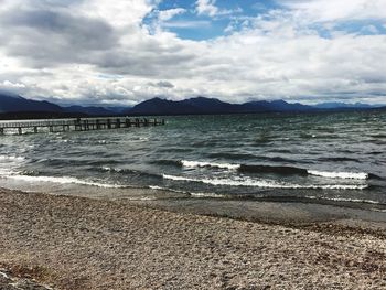 View of calm beach against cloudy sky