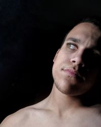Close-up portrait of young man against black background