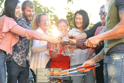 Friends toasting drinks while standing in yard