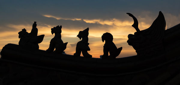 Low angle view of silhouette statue against sky