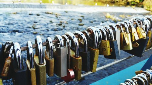 Close-up of padlocks hanging on railing by river