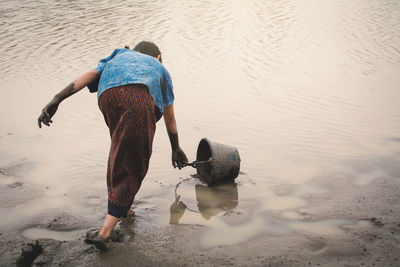 Girl filling water in bucket at beach