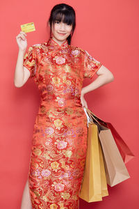 Young woman holding red umbrella against gray background
