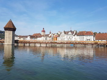 Buildings at waterfront against cloudy sky