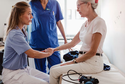 Doctor checking pulse of senior woman in medical examination room