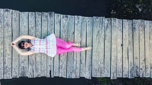 Woman with pink umbrella on wooden fence