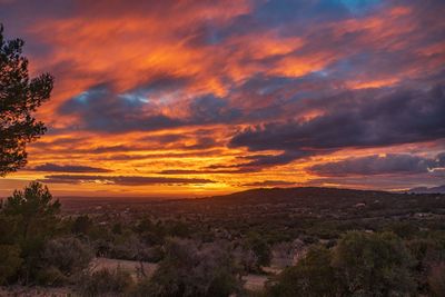 Scenic view of landscape against dramatic sky during sunset