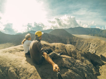 A couple is sitting at the edge of bromo volcano