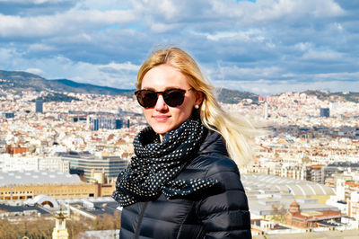 Portrait of young woman standing against cityscape