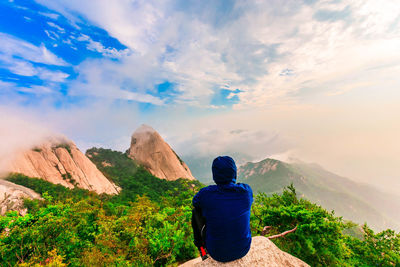 Rear view of man looking at mountains against sky