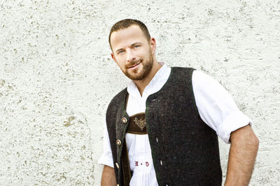 Portrait of smiling man standing against white wall