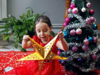 A little girl in a festive red dress holds a paper gold star decorative decor. new year 