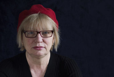 Portrait of mature woman with red cap against black background